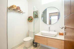 A modern bathroom with a glass shower enclosure, a round mirror, and a wooden vanity. - Mateo Villa Marvelous 6BR 2 Mins to Beach (Canggu)