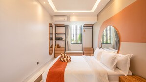 A modern hotel room with a bed, a wooden nightstand, a mirror, and a window with blinds. - Mateo Villa Marvelous 6BR 2 Mins to Beach (Tibubeneng)