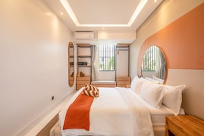 A modern hotel room with a bed, a wooden nightstand, a mirror, and a window with blinds. - Mateo Villa Marvelous 6BR 2 Mins to Beach (Canggu)