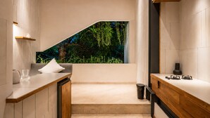 Een moderne keuken met een houten plafond, een inbouwfornuis en uitzicht op groen door een raam.