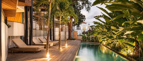 A poolside area with lounge chairs and a wooden deck.