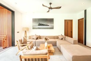 Een moderne woonkamer met een hoekbank, een houten salontafel en een plafondventilator.