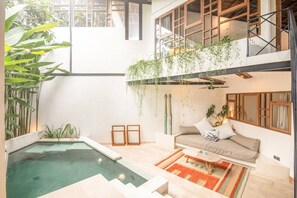 A spacious living area with a pool, a sofa, and a staircase leading to an upper level. - BA Villa 7 2BR Villa Art Dec Contemporary 2-br Art Deco Villa 800m to the Bea (Pererenan)