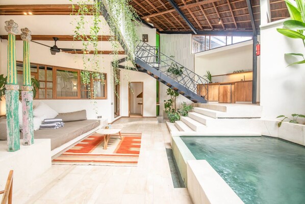 A spacious indoor area with a pool, a staircase, and a seating area with a sofa and a table. - BA Villa 7 2BR Villa Art Dec Contemporary 2-br Art Deco Villa 800m to the Bea (Pererenan)
