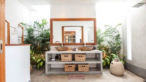 A modern bathroom with a large mirror, two sinks, wicker baskets, and potted plants. - Canggu Julia 2 in Dalung (Canggu)
