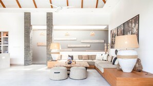 A spacious living area with a large sofa, ottomans, a wooden coffee table, and a large lamp. - Canggu Julia 2 in Dalung (Canggu)