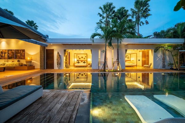 A modern resort with a swimming pool, wooden deck, and multiple rooms with large windows. - Canggu Julia 2 in Dalung (Tibubeneng)