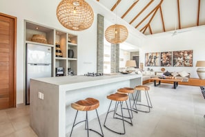 Una cucina moderna con un'isola centrale, sgabelli da bar e luci a sospensione.