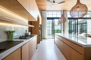 Une cuisine moderne avec des meubles en bois, un îlot central et des luminaires suspendus.