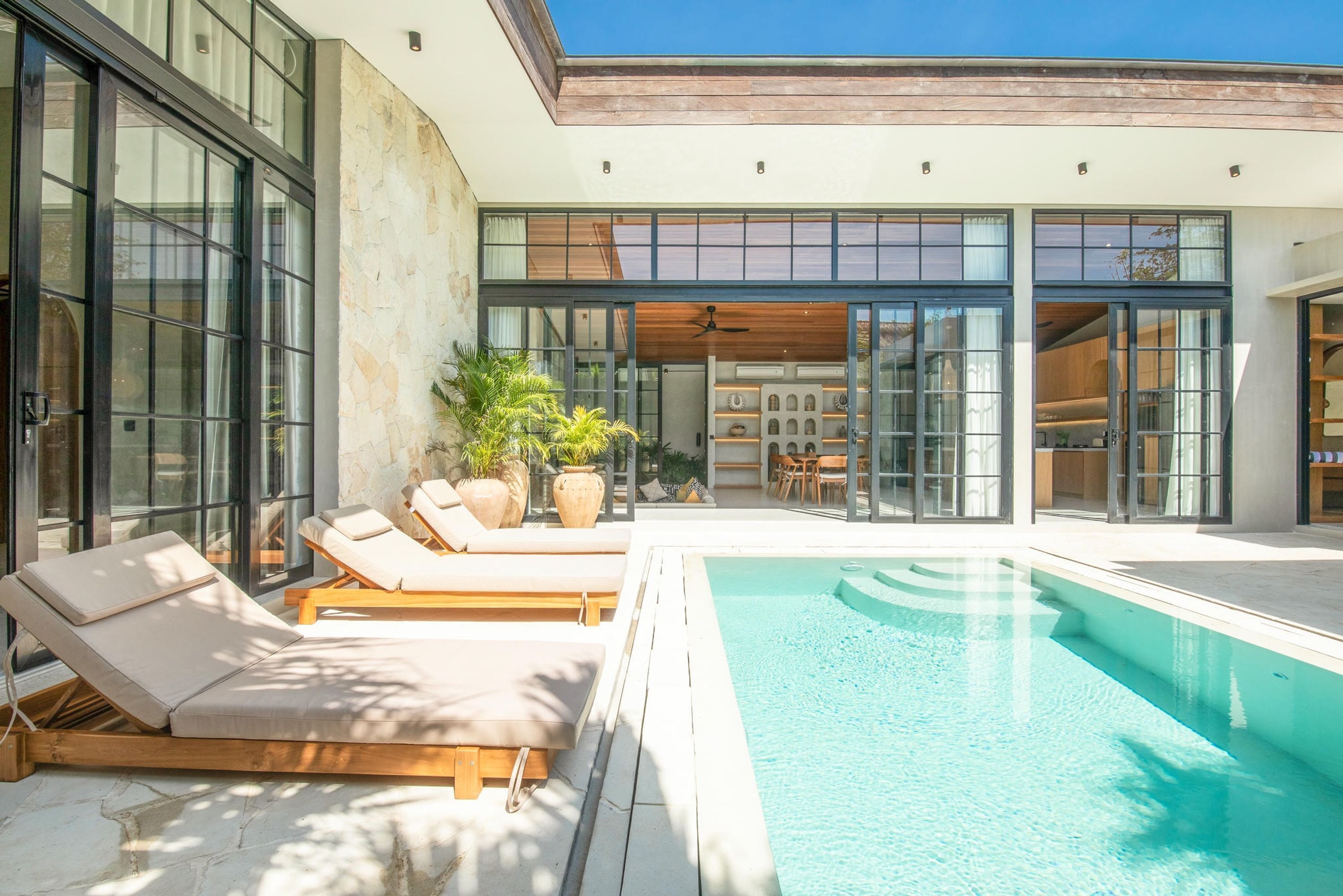 A modern outdoor pool area with lounge chairs and potted plants.