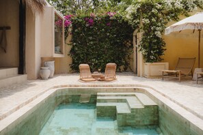 A swimming pool with lounge chairs and a table, surrounded by a garden with flowering plants. - Xanthe 3BR Villas 2 Mins to Ulu Beach (Pecatu)