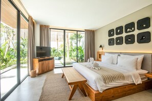 A modern bedroom with a large bed, a TV, and a view of greenery through large windows. - Swastamita in Dalung (Canggu)