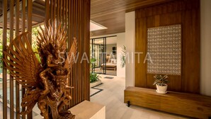 A modern interior with a wooden ceiling, a decorative golden statue, a patterned wall, and a potted plant. - Swastamita in Dalung (Canggu)