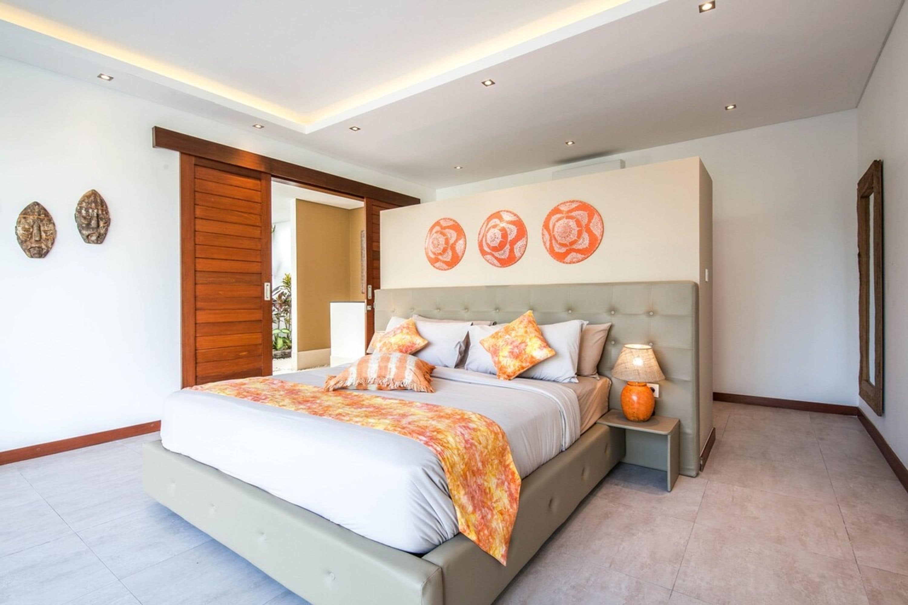 A modern bedroom with a large bed, a nightstand, and a wall-mounted lamp.
