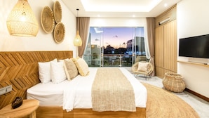 A modern hotel room with a large bed, a TV, and a balcony with a city view. - Sol N3 S in Dalung (Tibubeneng)