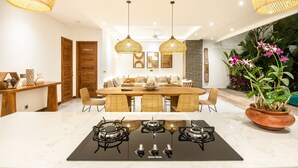 A modern kitchen with a central island, a dining area with a large table and chairs, and a ceiling fan. - Sol N3 S in Dalung (Tibubeneng)