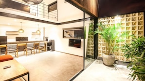 A modern kitchen with a dining area, a staircase, and a large potted plant. - Loft 1 App in Pererenan (Munggu)