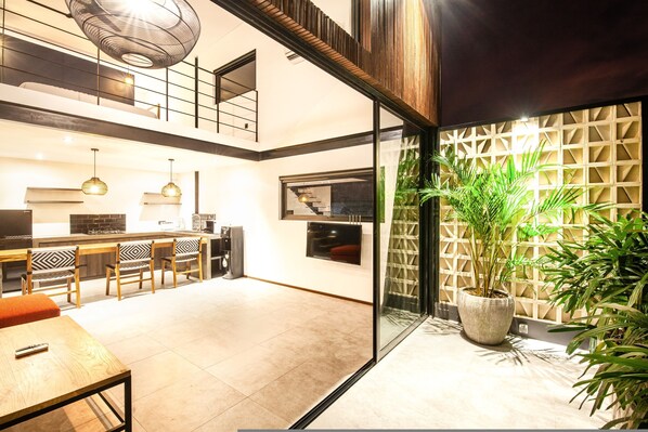 A modern kitchen with a dining area, a staircase, and a large potted plant. - Loft 1 App in Pererenan (Munggu)