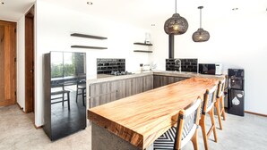 A modern kitchen with a wooden dining table, black appliances, and pendant lighting. - Loft 1 App in Pererenan (Munggu)
