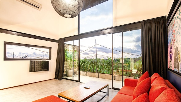 A modern living room with a large window, a sofa, a table, and a TV. - Loft 1 App in Pererenan (Munggu)