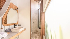 Un baño moderno con tocador de madera, un espejo grande y una ducha con piso de baldosas.