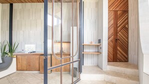 Una cocina moderna con encimera de madera, una división de vidrio y una puerta de madera con un diseño geométrico.