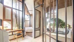 Un interior moderno con comedor, sofá y un gran ventanal que da a un espacio exterior.