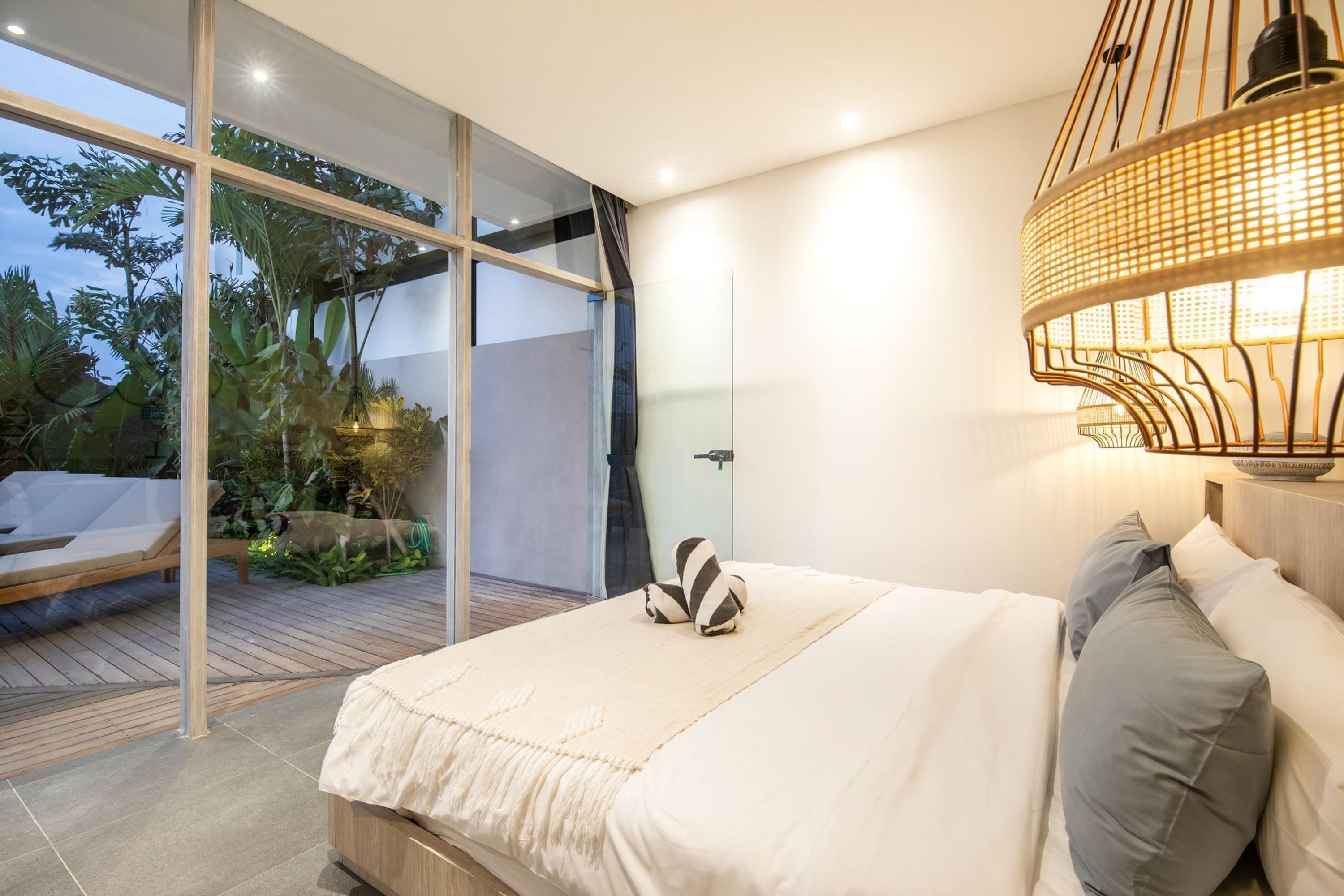 A modern bedroom with a large bed, a glass door leading to a balcony, and a unique hanging light fixture.