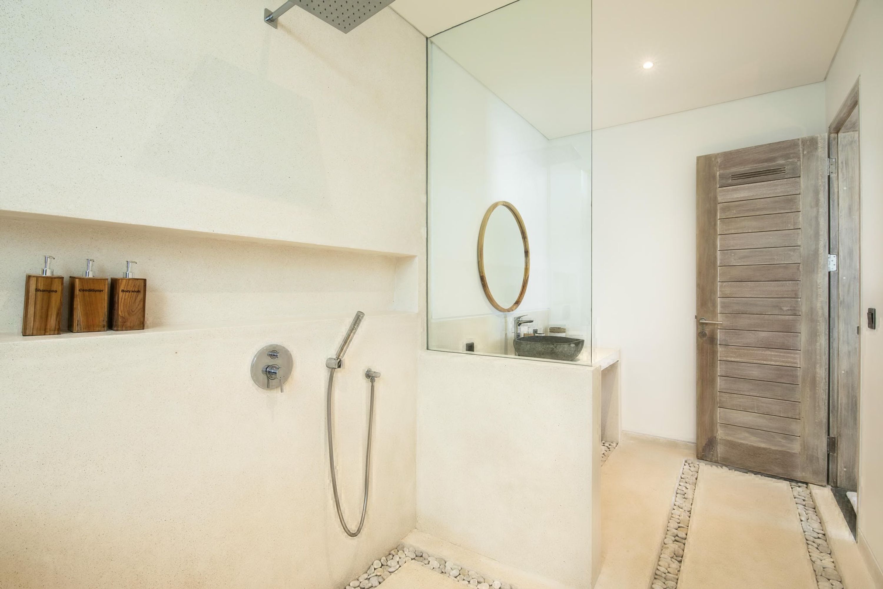 Ein modernes Badezimmer mit einer Duschkabine aus Glas, einer Holztür und einem kleinen Ablagebereich für Toilettenartikel.