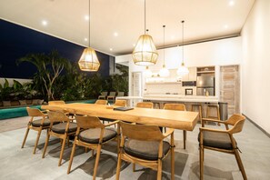 Una cucina moderna con isola centrale, sedie in legno e lampade a sospensione.