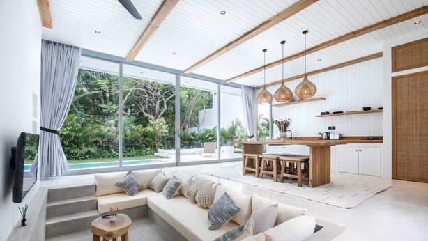 Een moderne woonkamer met een grote bank, een houten salontafel, en een eethoek met een keuken op de achtergrond.