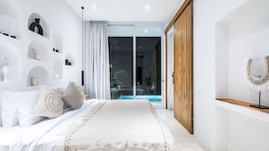 Een moderne slaapkamer met een groot bed, een schuifdeur naar een balkon en een minimalistische inrichting.