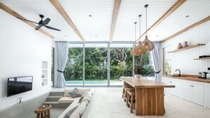 Een moderne keuken met een houten kookeiland, witte kasten en een groot raam met uitzicht op een tuin.