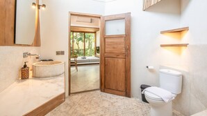 Un baño con puerta de madera, un lavabo redondo y un inodoro.