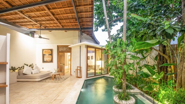 Un interior moderno con piscina, zona de estar y abundante vegetación.