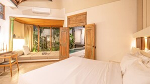 Un dormitorio con una cama grande, una silla de madera, un sofá y un ventanal corredero que da a una zona de piscina.