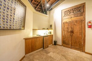 A kitchen with wooden cabinets, a sink, and a decorative wooden door. - BA Villa 4 1BR Lush 1-br Villa With Pool 4 Mins to Echo Beach (Canggu)