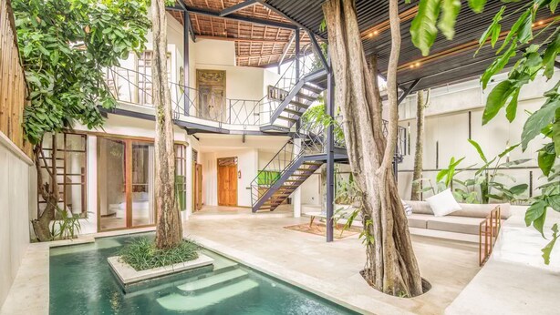 A spacious indoor area with a central pool, surrounded by trees and a staircase leading to upper levels. - BA Villa 10 2 BR Stylish 2-br Villa With Pool 800m Canggu Beach (Pererenan)