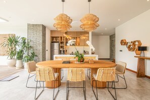Une cuisine moderne avec un îlot central, une table à manger en bois et des chaises en osier.