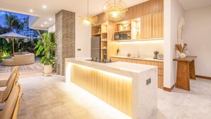 A modern kitchen with a central island, wooden cabinetry, and pendant lighting. - SOL n2 Villa in Dalung (Tibubeneng)
