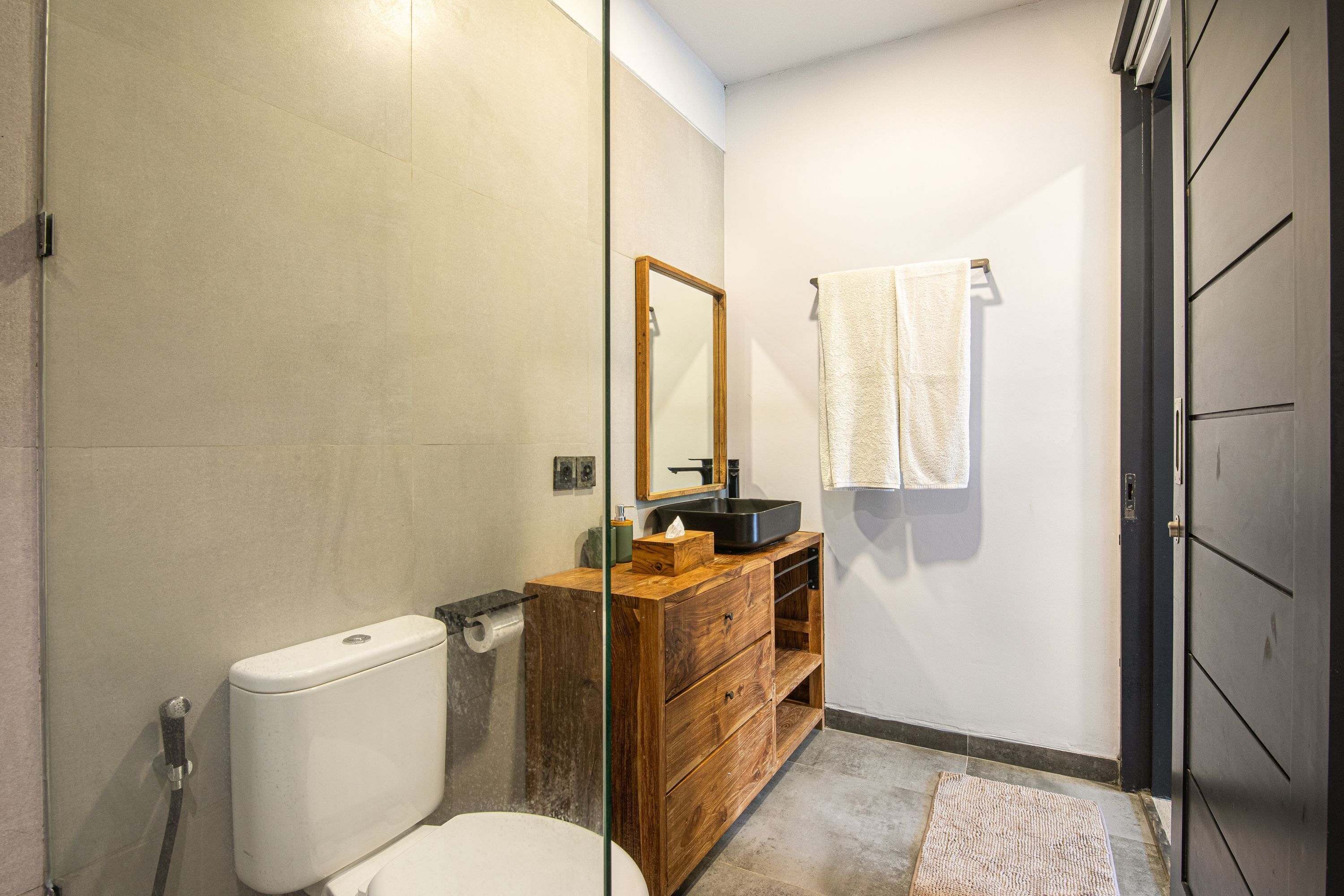A bathroom with a toilet, sink, and mirror.