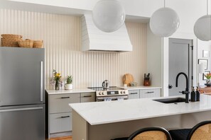 A modern kitchen with a central island, stainless steel appliances, and a large window. - Beltline Basilica (Atlanta)