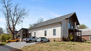 Une maison à deux étages avec un porche couvert, une allée et une cour gazonnée.