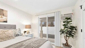 A bedroom with a bed, bedside table, lamp, and a potted plant. - Freshly Updated Hideaway in CDA’s Best Spot (Coeur d'Alene)