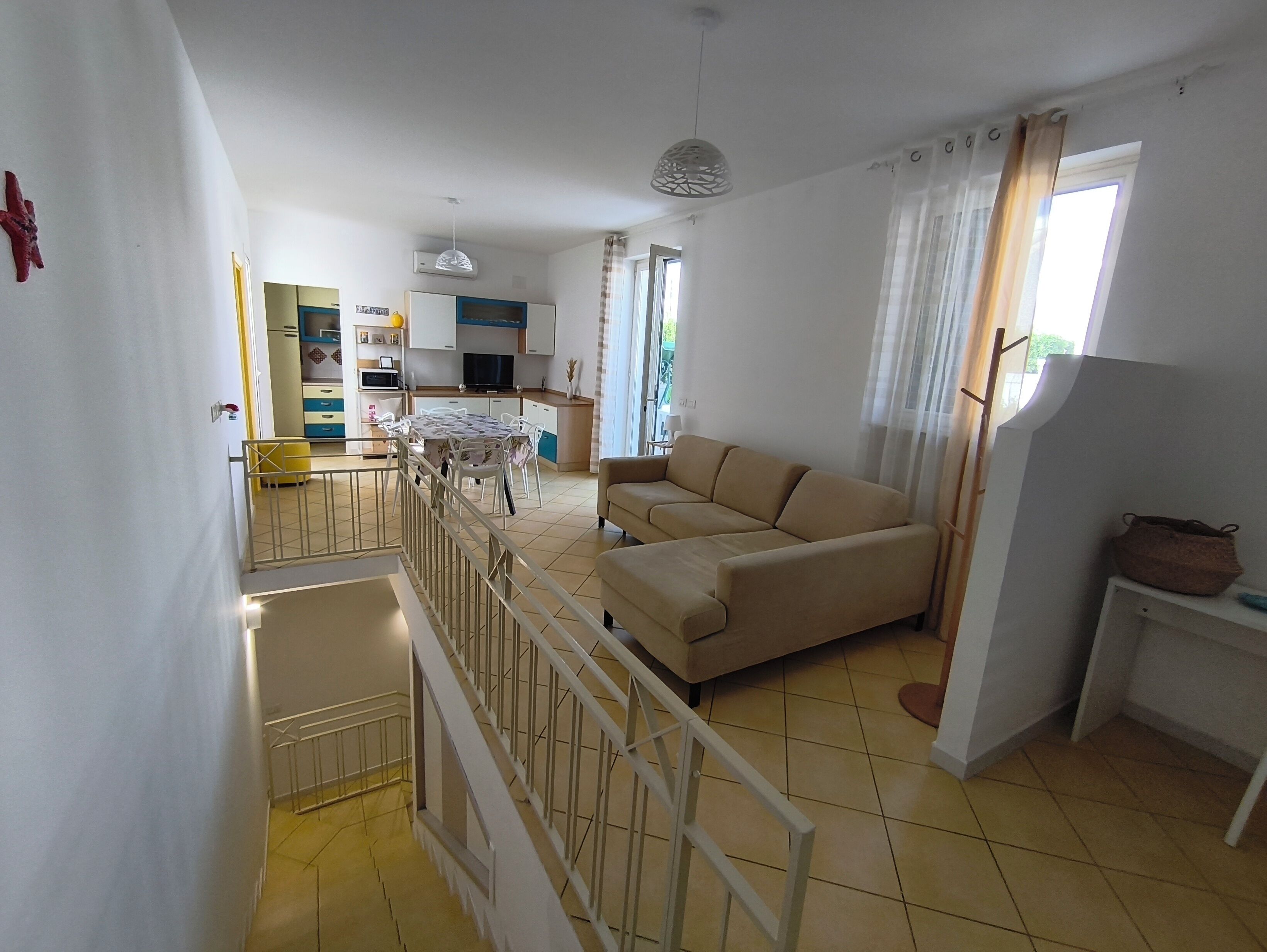A living room with a sofa, a dining table, and a kitchen area in the background.