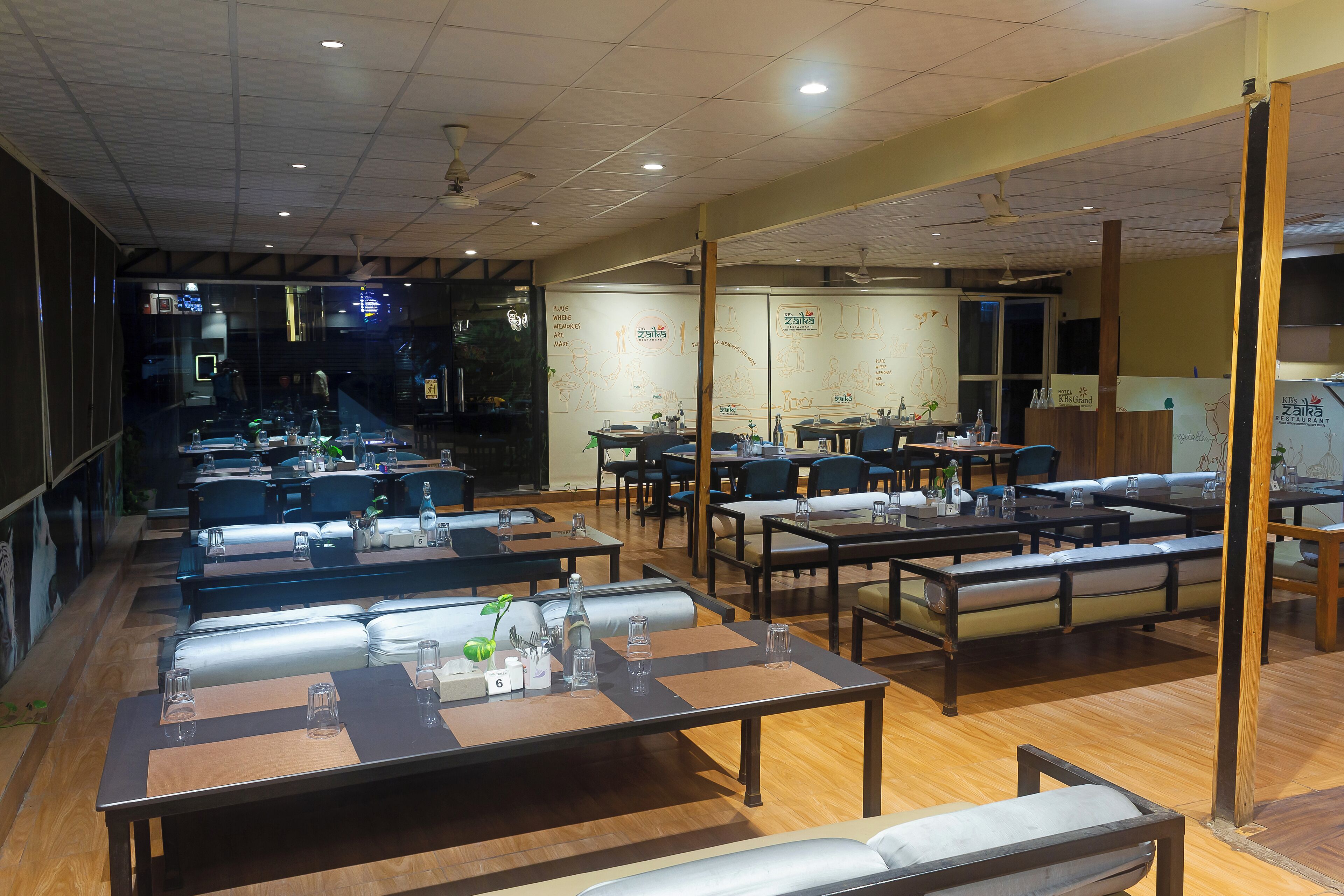 A restaurant interior with multiple dining tables and booths, ceiling fans, and a wall with a logo and text.