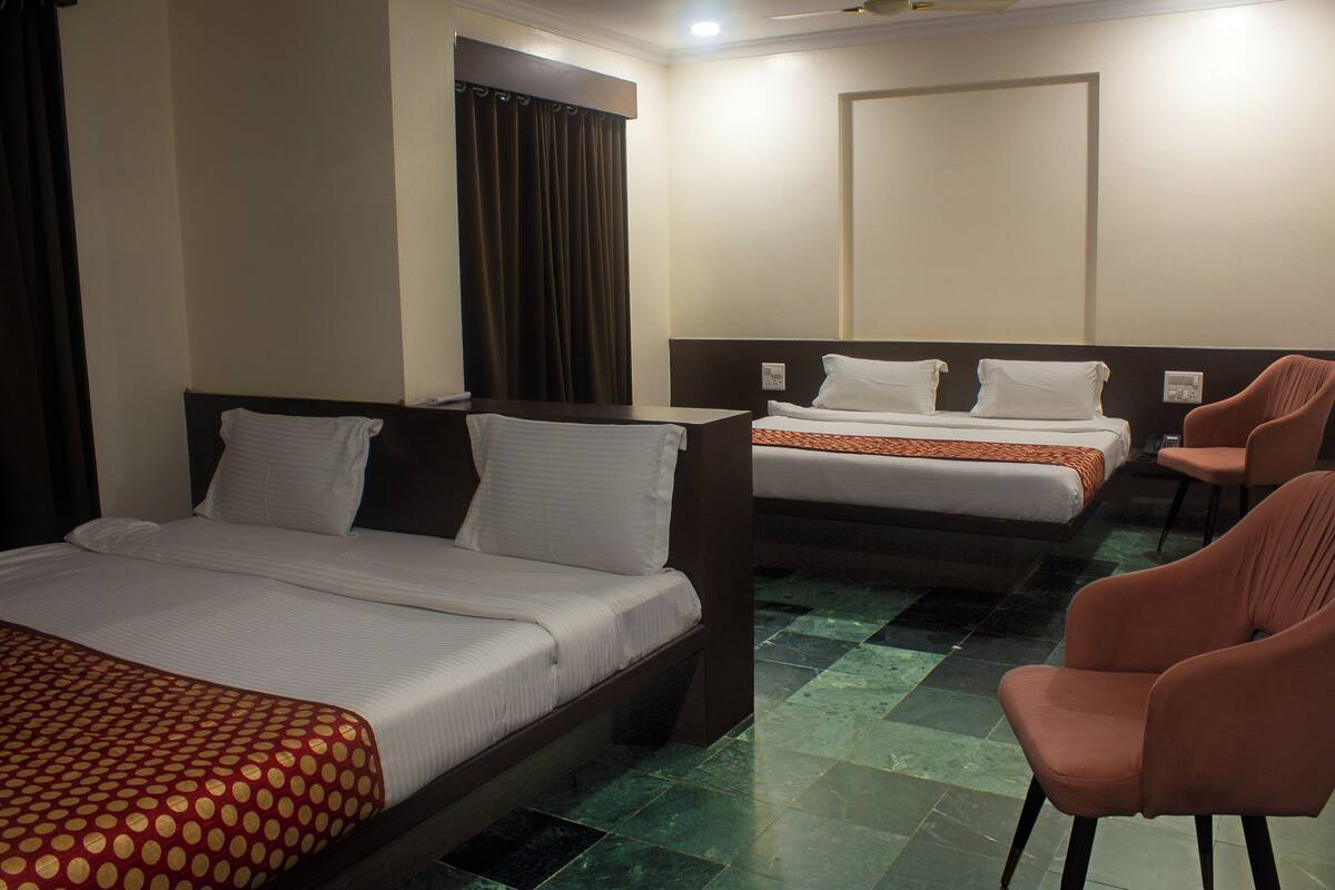A hotel room with two beds, a chair, and a curtain.