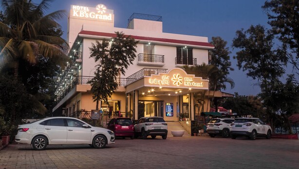 Un hotel con un cartel que dice "Hotel KB's Grand" y varios coches aparcados en la calle.