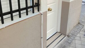 A white door with a brass handle, a black metal gate, and a small mailbox on the wall. - Apartmen with Gym 20 min from the center of Madrid (Leganés)