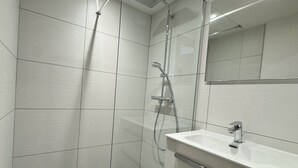 Un baño moderno con ducha, lavamanos y espejo.